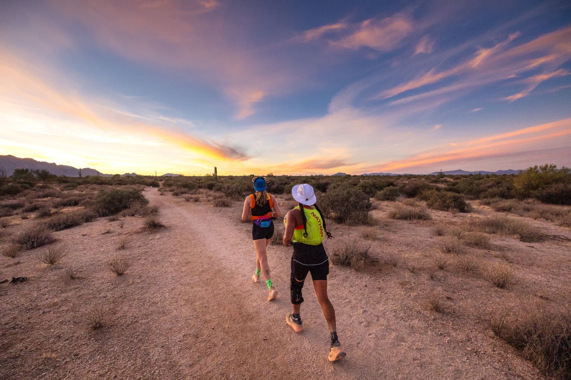 Two runners on a desert trail at sunset during Javelina Jundred